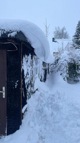 a snow covered house with a pile of snow on it at Ferienwohnung Wiesenblick in Seiffen in Kurort Seiffen