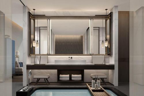 ein Bad mit einem Waschbecken und einem Spiegel in der Unterkunft Qingdao Marriott Hotel Jiaozhou in Qingdao