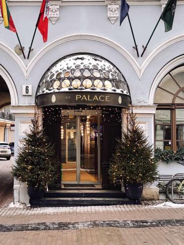 a entrance to a palace with two christmas trees in front at St Palace Hotel in Vilnius