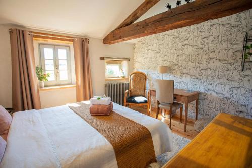 1 dormitorio con cama, mesa y escritorio en La Fée Capucine - Chambres et table d'hôtes - Espace bien-être et massages, en Saint-Galmier