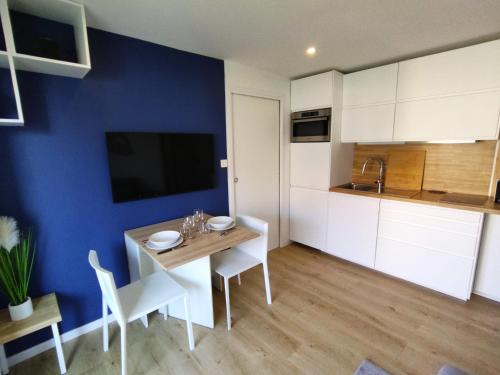 a small kitchen with a table and a blue wall at Très bel appartement à 2 minutes de la plage de Tanchet - 4 pers in Les Sables-d'Olonne