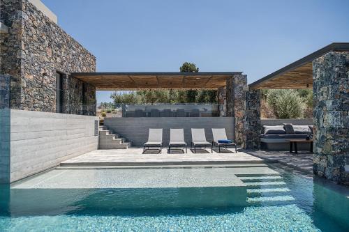a swimming pool with two lounge chairs next to a house at Brand new Villa Eleftheria BY APOKORONAS-VILLAS in Plaka
