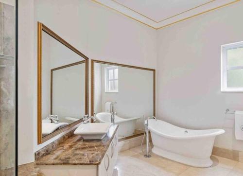 un bagno con due lavandini, una vasca e due specchi di The White House a Johannesburg