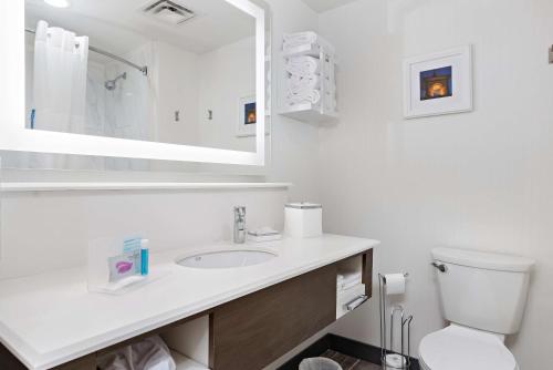W białej łazience znajduje się umywalka i lustro. w obiekcie Hampton Inn Kansas City - Downtown Financial District w mieście Kansas City