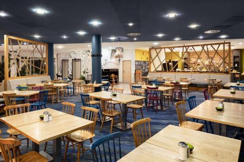 a restaurant with wooden tables and chairs and a lot of tables at Vienna House Easy by Wyndham Bratislava in Bratislava