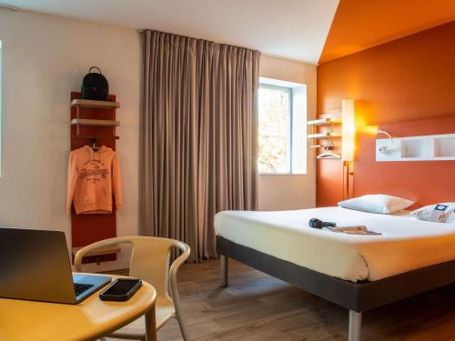 a bedroom with a bed and a desk with a laptop at ibis budget Paris Clichy Mairie in Clichy