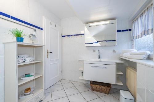 a white bathroom with a sink and a mirror at Haus Tinchen in Westerland (Sylt)
