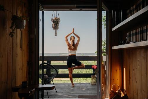 uma mulher a fazer uma pose de yoga à porta de uma casa em Casa Quint em Csákberény