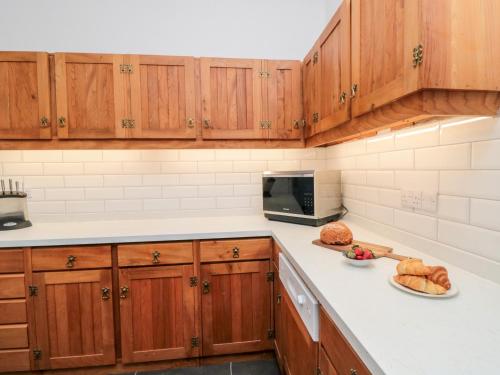 a kitchen with wooden cabinets and a counter top with bread at The Grange in Whitby