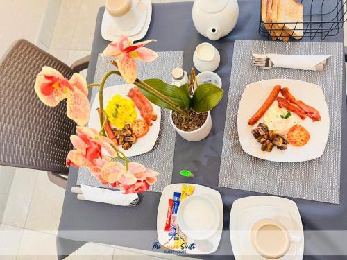 een tafel met borden eten en bloemen erop bij The Curve Suite Guest House 