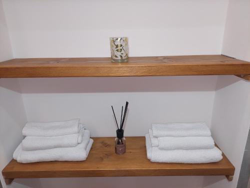 ein Holzregal mit drei Handtüchern und einer Vase in der Unterkunft Novi Outlet Apartment in Novi Ligure