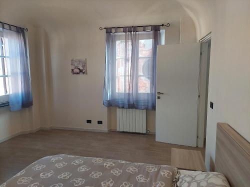a bedroom with a bed and two windows at Novi Outlet Apartment in Novi Ligure