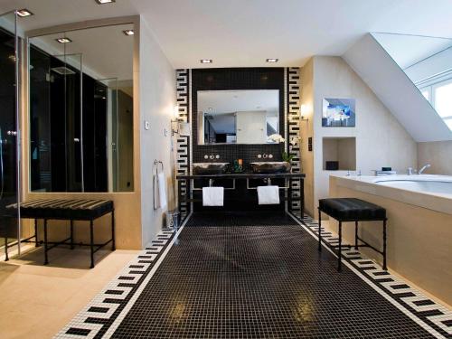 ein Badezimmer mit einer Badewanne und einem großen Spiegel in der Unterkunft Sofitel Paris Le Faubourg in Paris