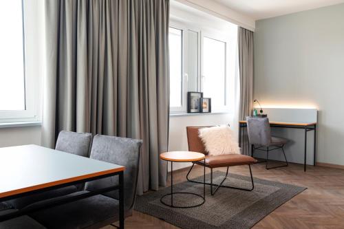 - un salon avec un canapé, une table et des chaises dans l'établissement LOGINN Hotel Offenbach, à Offenbach-sur-le-Main