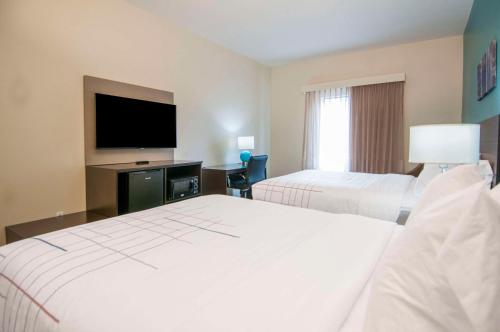 a hotel room with two beds and a flat screen tv at Sleep Inn & Suites in Tuscaloosa