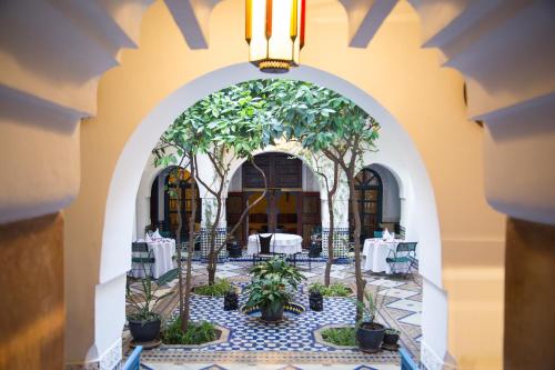 an archway with tables and trees in a restaurant at Ryad El Borj in Marrakech