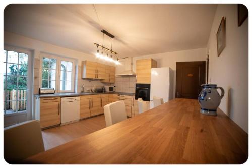 une cuisine avec une grande table en bois et un vase. dans l'établissement La Chaumière Alsacienne, à Ebersmunster