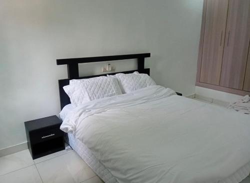 ein Bett mit weißer Bettwäsche und Kissen in einem Schlafzimmer in der Unterkunft Luxury 2- Apartment Furnished luxury residence in Cocody