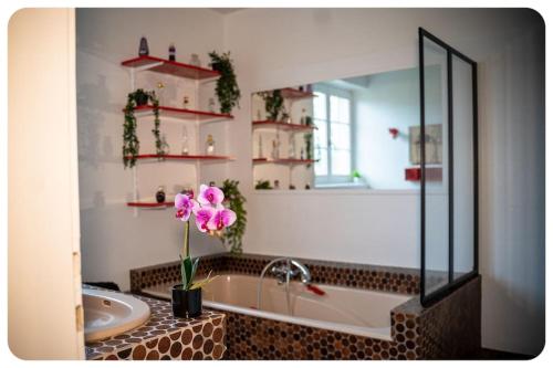 ein Badezimmer mit einem Waschbecken und einer Badewanne mit einer rosa Blume in der Unterkunft La Chaumière Alsacienne 