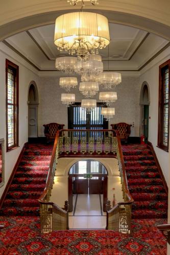a large lobby with a staircase and chandelier at Trafford Hall Hotel Manchester, Trademark Collection by Wyndham in Manchester