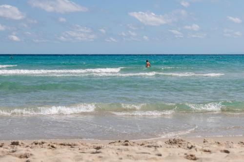 a person is in the water at the beach at Amareclub Baia Dei Turchi Resort - Adults Only in Otranto