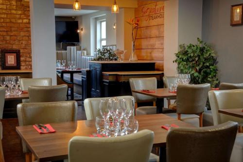 a restaurant with tables and chairs and a piano at Trafford Hall Hotel Manchester, Trademark Collection by Wyndham in Manchester