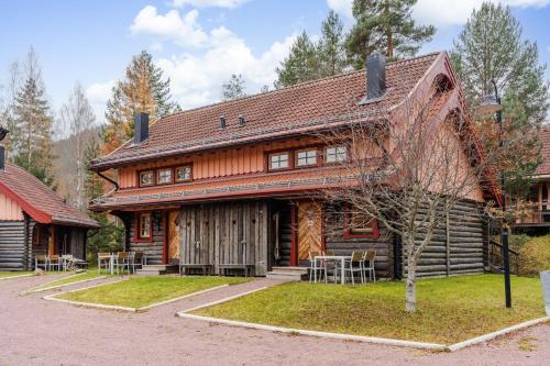 ein Blockhaus mit Tischen und Stühlen davor in der Unterkunft Sagolandsbyn in Mora