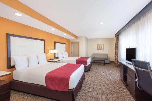 a hotel room with two beds and a flat screen tv at Ramada by Wyndham Culver City in Los Angeles