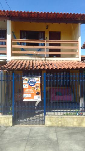 a building with a sign in front of a fence at Hospedaria Meu lar in Rio das Ostras