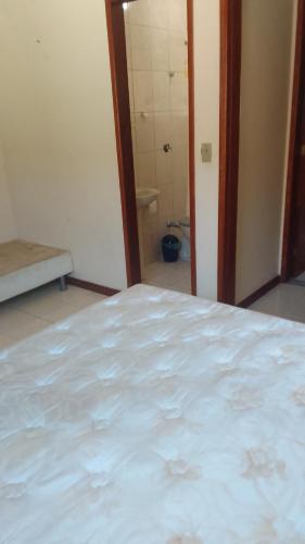 a white bed in a room with a bathroom at Hospedaria Meu lar in Rio das Ostras