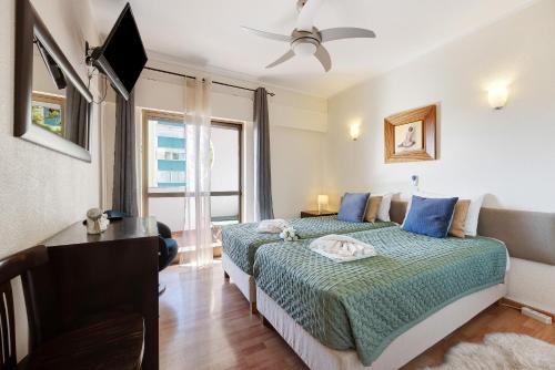 a bedroom with a bed and a desk and a window at House Amendoeiras in Vilamoura