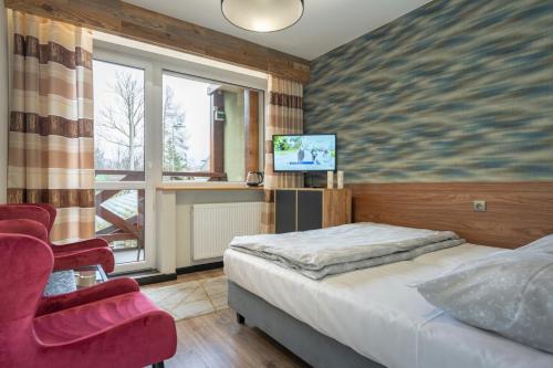 sypialnia z łóżkiem, krzesłem i telewizorem w obiekcie Willa Elena w Szklarskiej Porębie