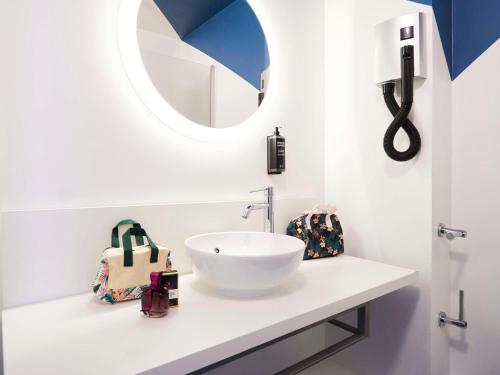 een badkamer met een witte wastafel en een spiegel bij ibis Styles Toulon Centre Port in Toulon