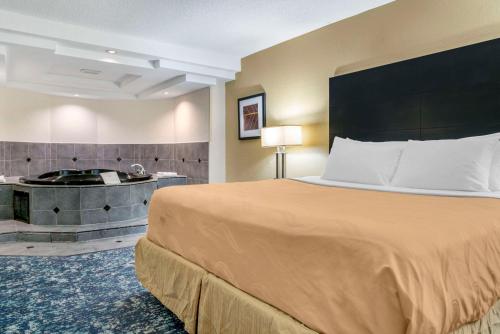 a hotel room with a bed and a bath tub at Quality Inn & Suites Banquet Center in Livonia