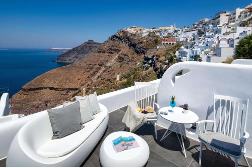 a balcony with white chairs and a view of the ocean at Athina Luxury Suites in Fira