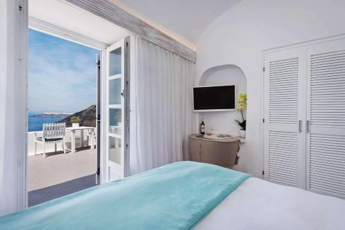 a bedroom with a bed and a view of the ocean at Athina Luxury Suites in Fira