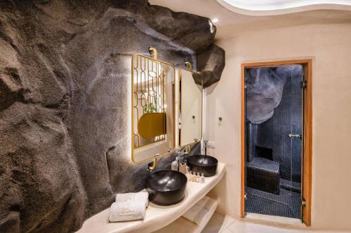 a bathroom with a large rock wall at Athina Luxury Suites in Fira