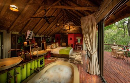 a bedroom with a bed and a tub in a room at Jaci's Lodges in Madikwe Game Reserve