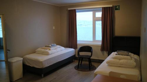 um quarto com 2 camas, uma janela e uma cadeira em Tangahús Guesthouse em Borðeyri