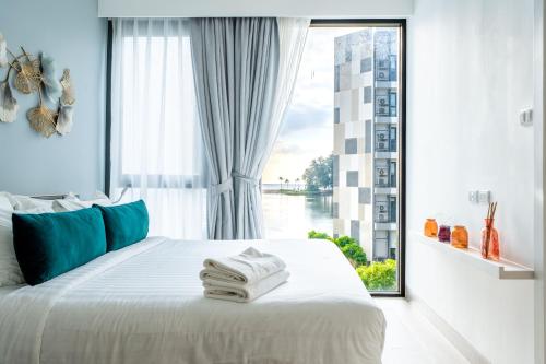 a bedroom with a white bed with a large window at Cassia Residences by NLA in Bang Tao Beach