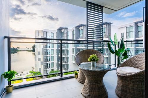 a balcony with a table and chairs and a large window at Cassia Residences by NLA in Bang Tao Beach