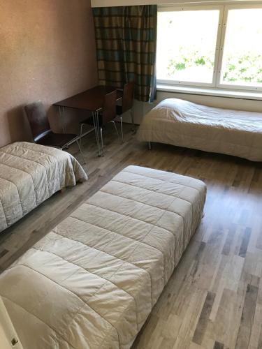 a bedroom with two beds and a desk and a table at Leo Hotelli in Kouvola