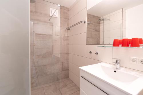 ein Bad mit einer Dusche, einem Waschbecken und einem Spiegel in der Unterkunft White House Kaprun in Kaprun