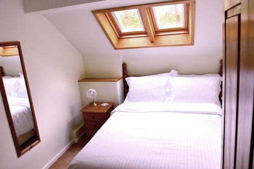 a bedroom with a white bed and a mirror at Hafannedd Cottage - riverside views in Corwen