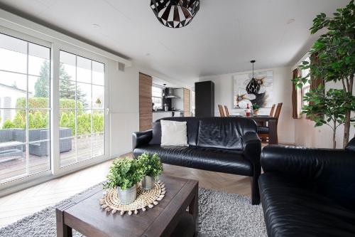 a living room with a black leather couch and a table at Holiday Inn 48 Oisterwijk # Hygiëne # Airport Eindhoven # Airco # Bosrijk # Hiking & Biking # Efteling # Safaripark in Oisterwijk