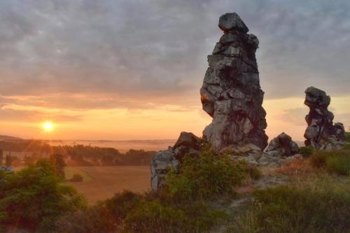 a rock formation on a hill with the sunset in the background at Ferienhaus Waldliebe in Hüttenrode