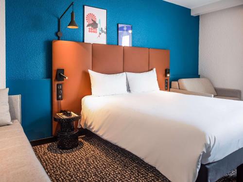 Schlafzimmer mit einem großen weißen Bett und blauen Wänden in der Unterkunft ibis La Baule Pornichet Plage in Pornichet