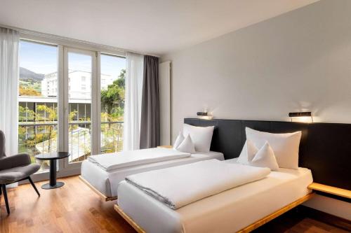 a hotel room with two beds and a window at Vienna House by Wyndham Martinspark Dornbirn in Dornbirn