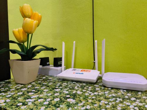 two electronics on a table with a vase with yellow tulips at IRDINA HOMESTAY forMuslims - Changlun in Changlun