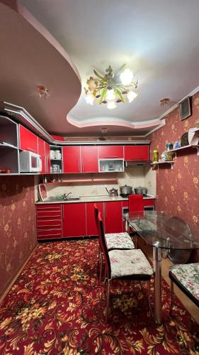a kitchen with red cabinets and a table and chairs at Хостел in Bishkek
